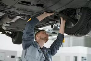 A technician working on the underside of a car