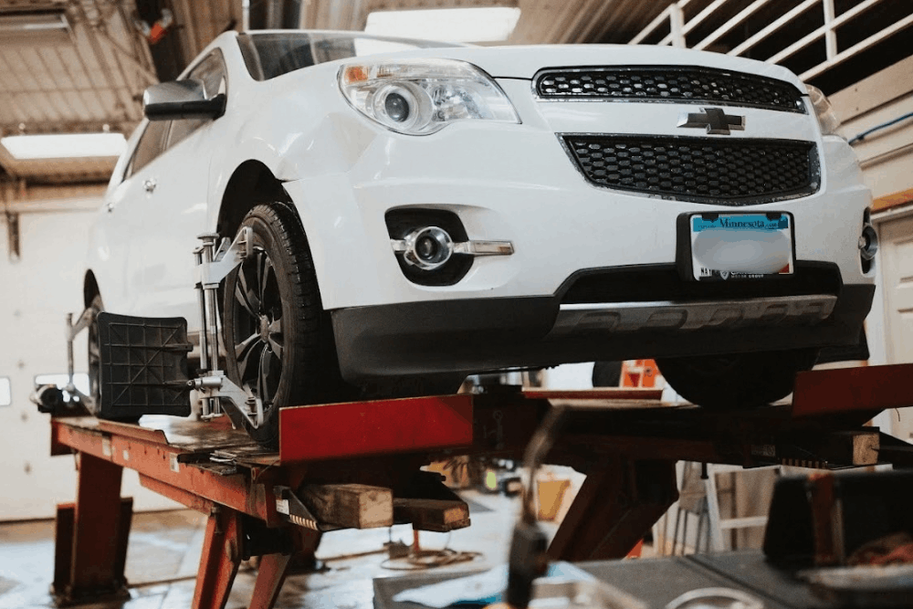Car shaking, auto repair in Watertown, MN at Arvu Auto. Image of a white Chevrolet SUV on an alignment rack with sensors attached to the wheels to support proper handling and even tire wear.