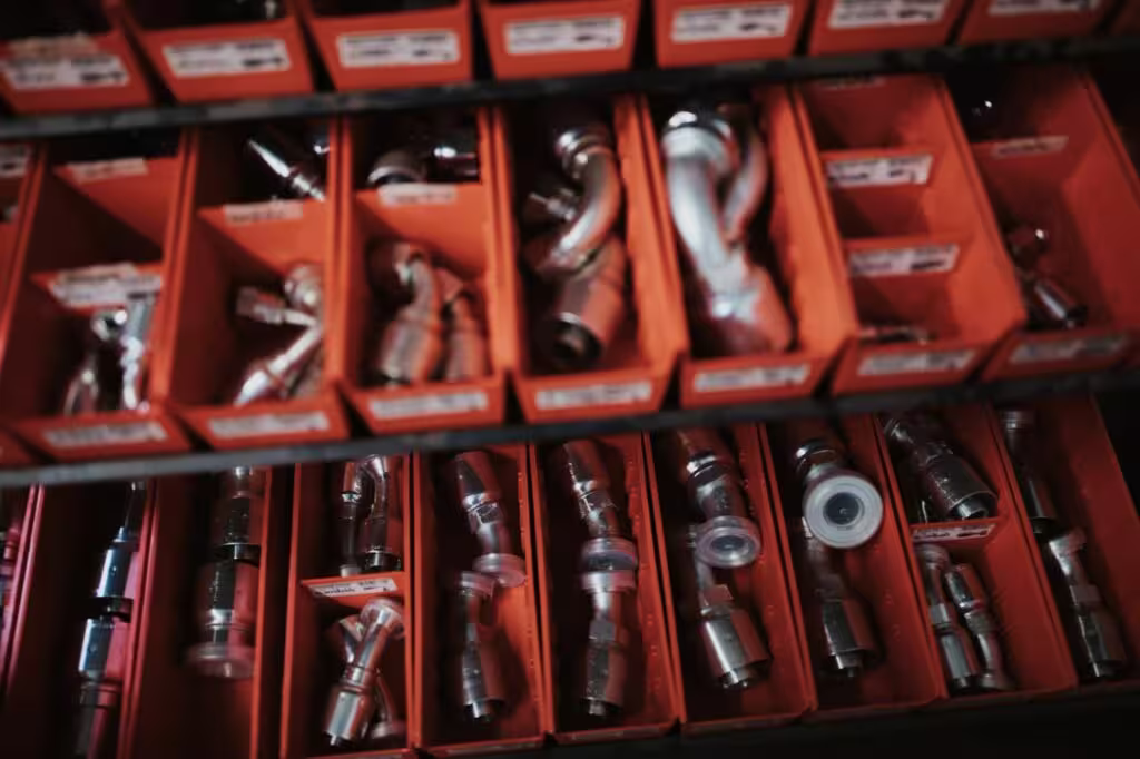 Organized orange storage bins filled with metal automotive fittings and connectors.