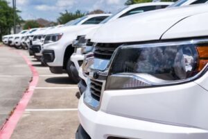Fleet of white Chevrolet SUVs parked in a row, reflecting the sky and surroundings.