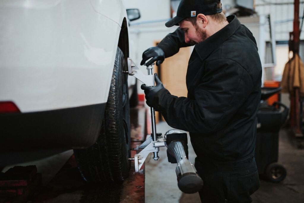 Mechanic adjusting car wheel alignment in a garage.