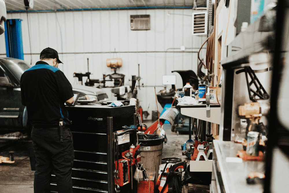 auto repair near Rassat, MN at Arvu Auto. A Mechanic working in a well-equipped garage with various tools and vehicles, showcasing a professional repair environment.