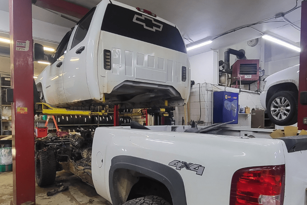 auto repair near Winsted, MN at Arvu Auto. Chevrolet 4x4 truck undergoing major service with the cab lifted, highlighting frame and engine access in a well-equipped shop.