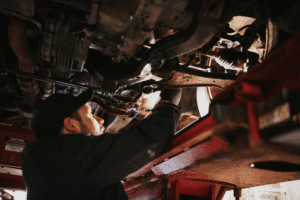Auto repair in Long Lake, MN by Arvu Auto. Image of an auto mechanic performing undercar repair on a vehicle lifted in the shop, highlighting the shop’s commitment to precise diagnostics, quality workmanship, and reliable vehicle performance.