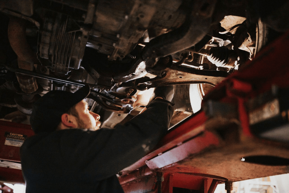 Auto repair in Long Lake, MN by Arvu Auto. Image of an auto mechanic performing undercar repair on a vehicle lifted in the shop, highlighting the shop’s commitment to precise diagnostics, quality workmanship, and reliable vehicle performance.