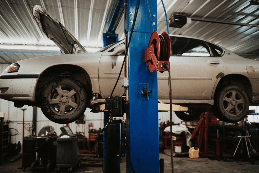 Auto repair near Kimball, MN by Arvu Auto. Image showing a white sedan lifted in the shop with the hood open, highlighting professional diagnostics and repair services for local drivers.