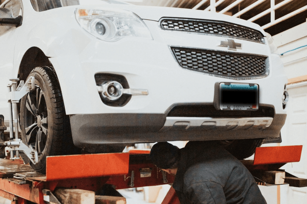 Auto repair near Waconia, WN by Arvu Auto. Image showing a white Chevrolet SUV on an alignment rack with sensors attached to the wheels, highlighting precision alignment services for safe and smooth driving.
