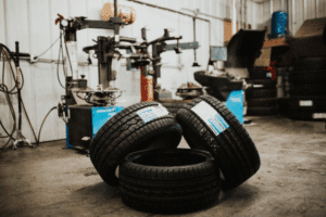 Tire tread, auto repair in Long Lake, MN by Arvu Auto. Image of new vehicle tires stacked inside an auto repair shop near tire mounting equipment, highlighting proper tire selection, tread quality, and professional installation for improved traction and road safety.