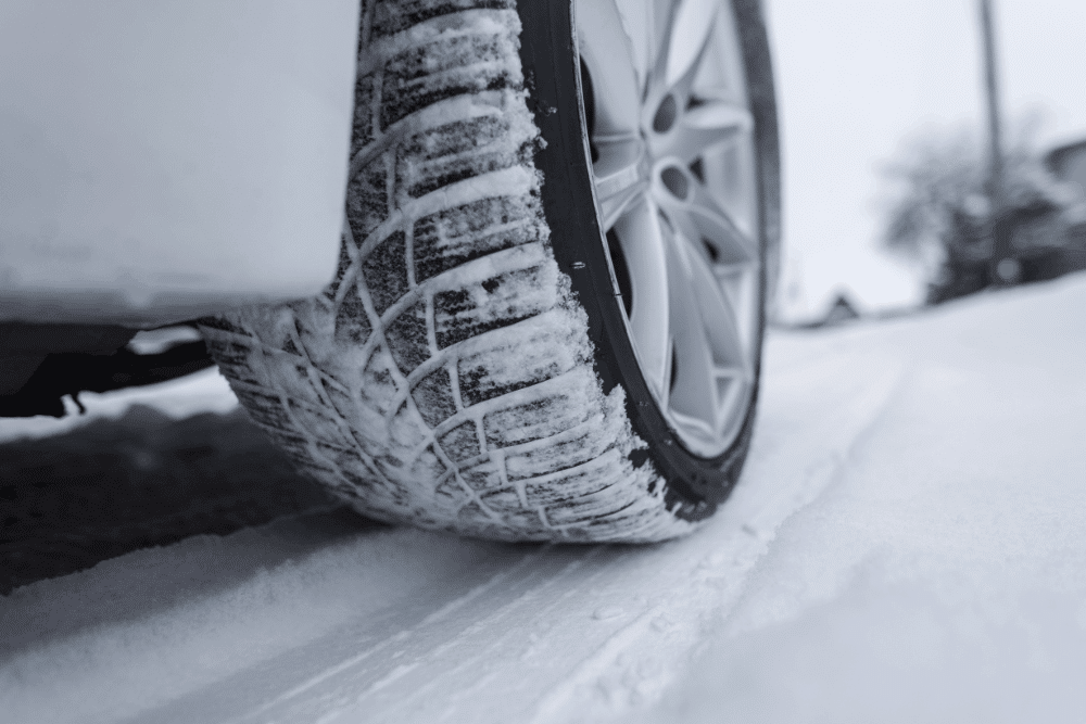 Low tread, auto repair in Long Lake, MN by Arvu Auto. Image of a vehicle tire driving on a snowy road, highlighting the importance of proper tread depth, winter traction, and vehicle safety in cold driving conditions.