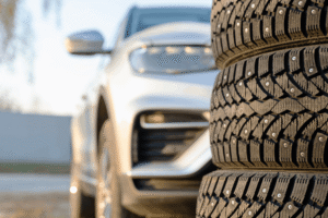 Tire inspection, auto repair in Long Lake, MN by Arvu Auto. Image of stacked winter tires with deep tread and studs in front of a vehicle, highlighting professional tire safety checks and seasonal tire services for improved traction and control.