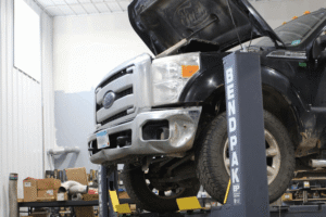 Diesel repair in Cokato, MN, at Arvu Auto. Image of Ford Super Duty diesel truck on a vehicle lift with the hood open, illustrating professional diesel engine diagnostics, maintenance, and repair services at an automotive repair shop.