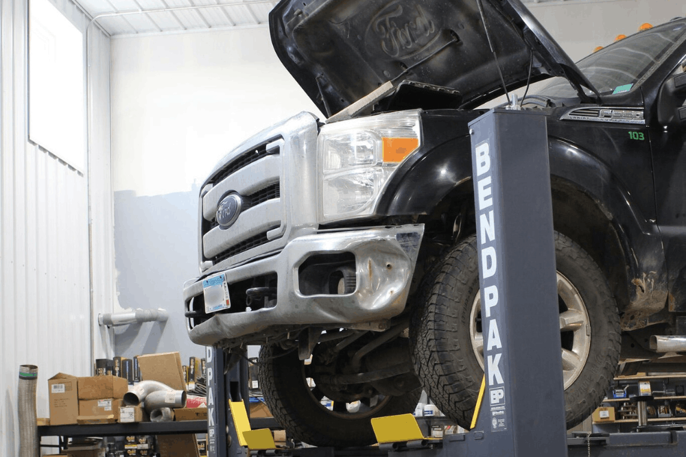 Diesel repair in Cokato, MN, at Arvu Auto. Image of Ford Super Duty diesel truck on a vehicle lift with the hood open, illustrating professional diesel engine diagnostics, maintenance, and repair services at an automotive repair shop.