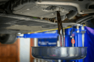 Fluid services, auto repair in Cokato, MN at Arvu Auto. Image of used engine oil draining from a vehicle into a collection pan during routine maintenance to help protect engine performance, reliability, and long-term vehicle health.