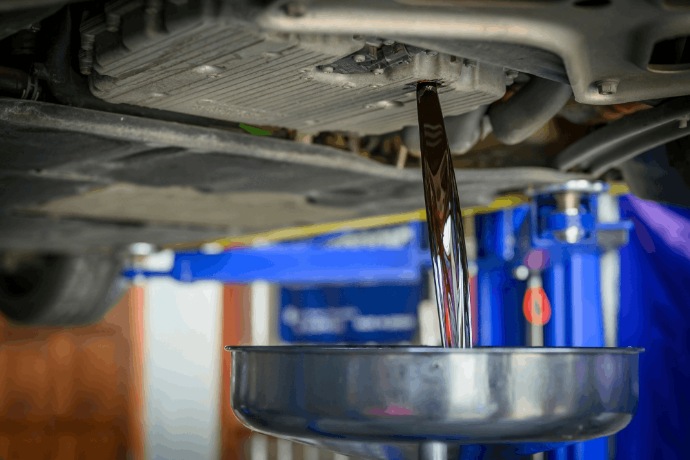 Fluid services, auto repair in Cokato, MN at Arvu Auto. Image of used engine oil draining from a vehicle into a collection pan during routine maintenance to help protect engine performance, reliability, and long-term vehicle health.