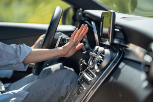 car a/c repair, auto repair in Long Lake, MN at Arvu Auto. Driver’s hand checking airflow from dashboard vents, highlighting potential issues with the vehicle’s a/c system.
